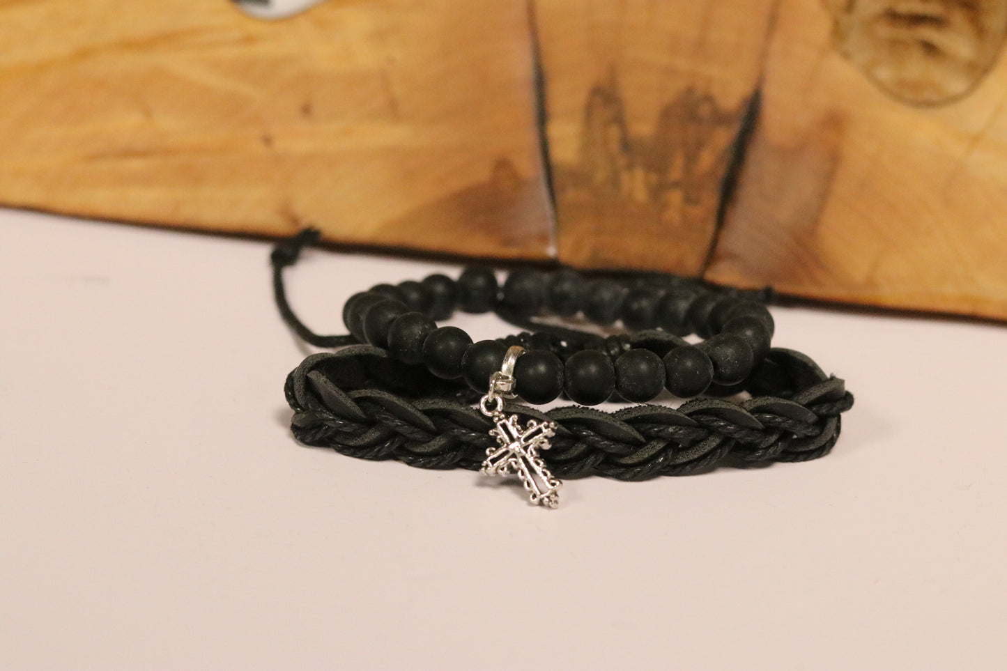 Black braided bracelet with a silver charm on a wooden surface