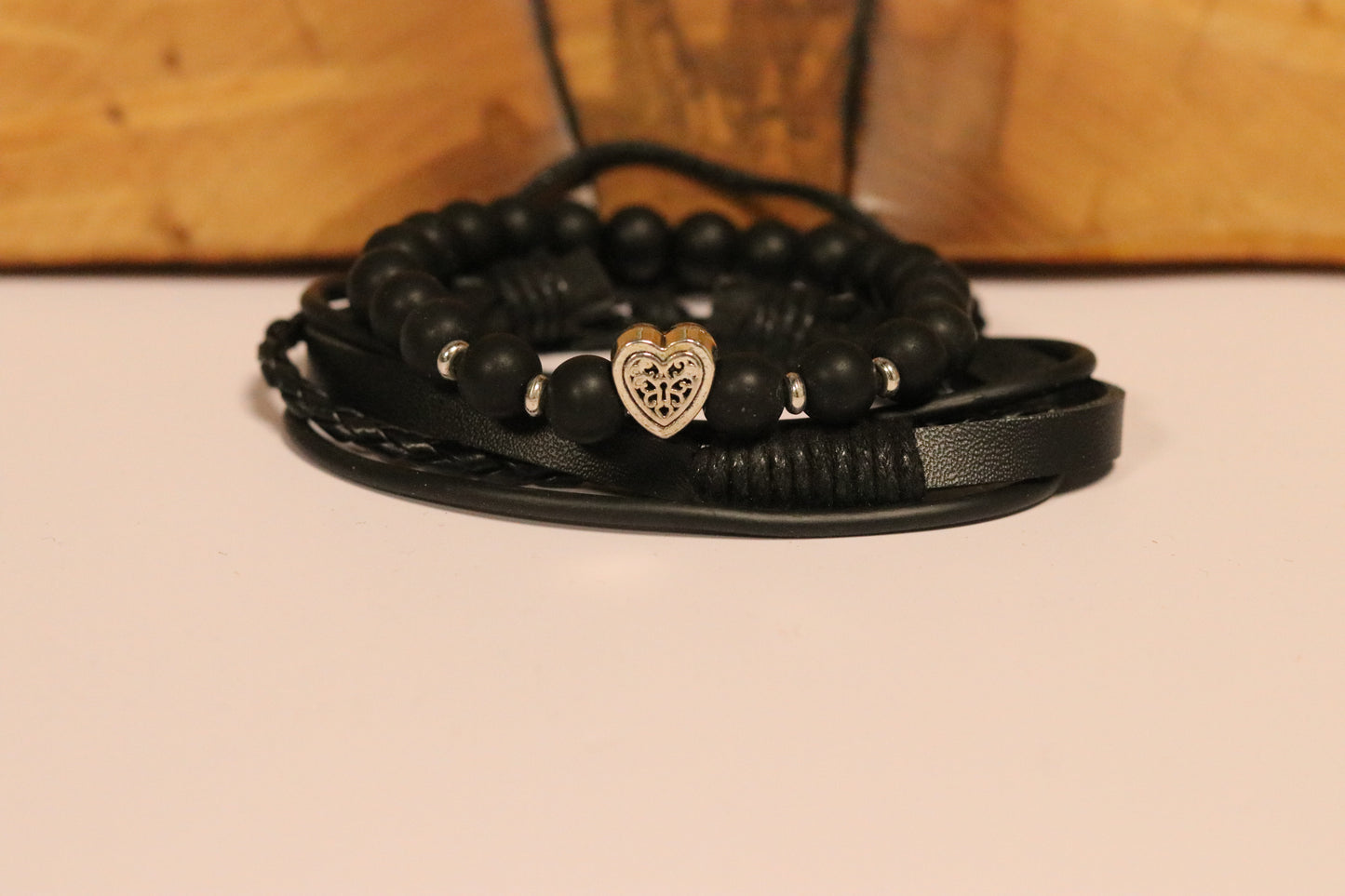 Black beaded bracelet with a heart charm on a beige surface
